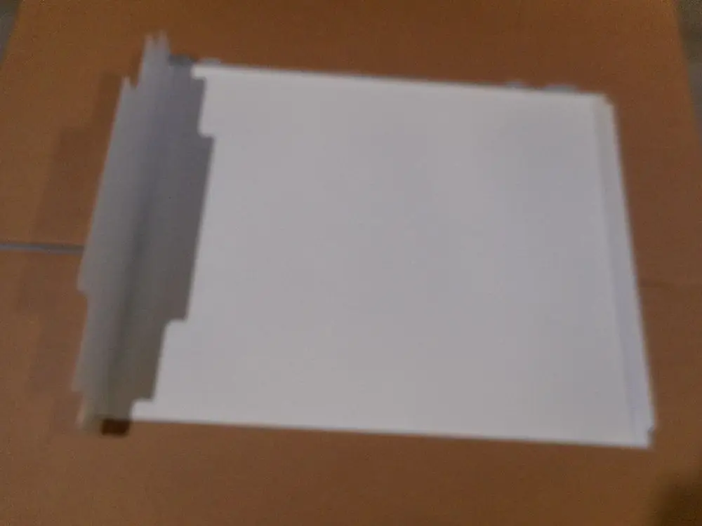 Weißes Bauteil von Remeha mit einer flachen Oberfläche und Ausschnitten an den Kanten, platziert auf einem neutralen Untergrund.